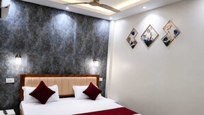 Une chambre d’hôtel avec un lit, une table de chevet, une lampe fixée au mur et un ventilateur de plafond.