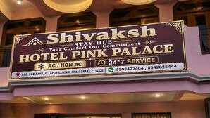 Une enseigne d’hôtel portant les noms « Shivaksh » et « Hotel Pink Palace », indiquant un service disponible 24 heures sur 24, 7 jours sur 7.