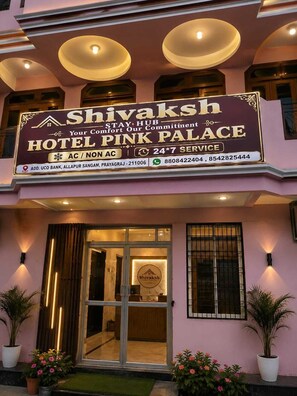Et hotelskilt med teksten 'Shivaksh' og 'Hotel Pink Palace', der angiver døgnåben service.