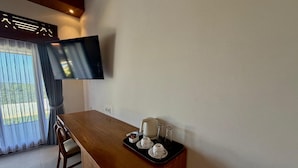 Une pièce avec un comptoir de bar en bois, un téléviseur fixé au mur et un coin repas avec une chaise.