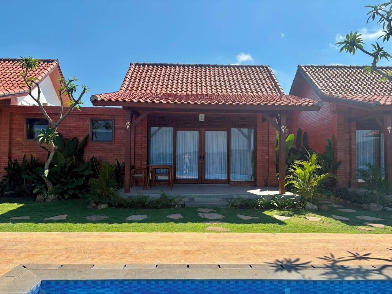 Una casa de dos pisos con techo de tejas, un porche delantero y una piscina.