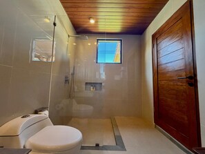 A bathroom with a shower, toilet, and a wooden door. - Atta Residence (Karangasem)