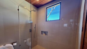 Une salle de bain moderne avec une douche à parois de verre, des toilettes et une petite étagère contenant des articles de toilette.