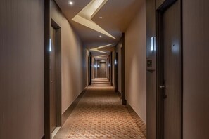 A hotel hallway with a carpeted floor, wooden doors, and recessed lighting. - Crystal  Hotel Tianjin Jinwan Plaza (Tianjin)