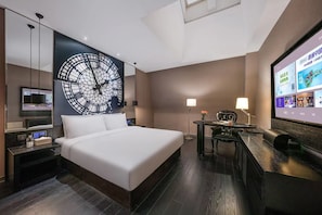 A hotel room with a large bed, a desk with a chair, a TV, and a wall-mounted clock. - Crystal  Hotel Tianjin Jinwan Plaza (Tianjin)