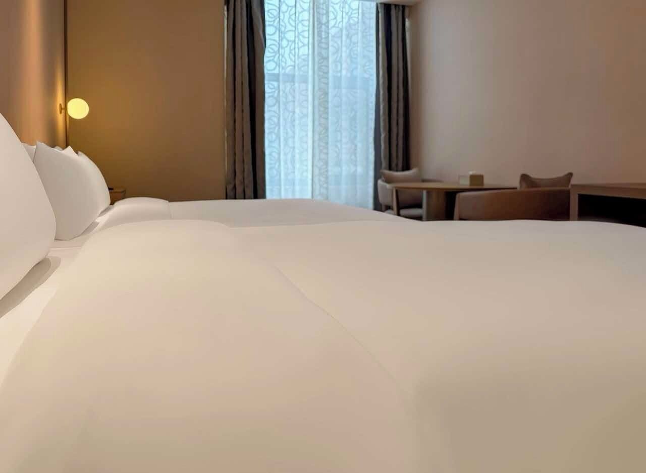 Una habitación de hotel con una cama grande, una mesita pequeña y una silla.
