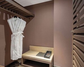 A small, enclosed space with a wooden bench, a white robe hanging on a rack, and a small table with a book. - Crystal  Hotel Tianjin Jinwan Plaza (Tianjin)