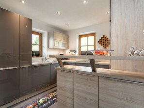 A modern kitchen with a built-in refrigerator, wooden cabinets, and a central island. - Exclusive holiday apartment with mountain view (Kirchberg in Tirol)