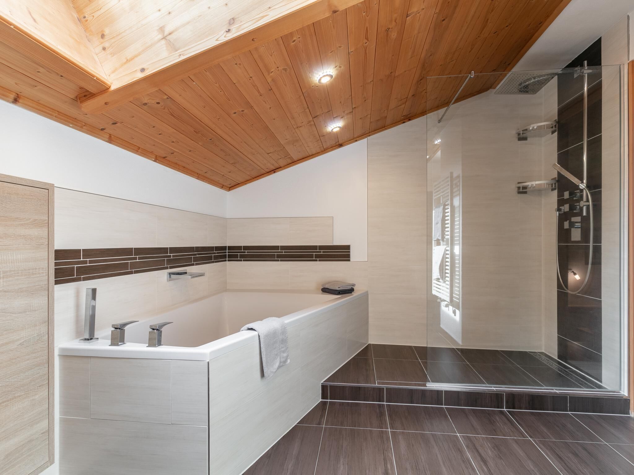 Een moderne badkamer met een bad, douche en houten plafond.