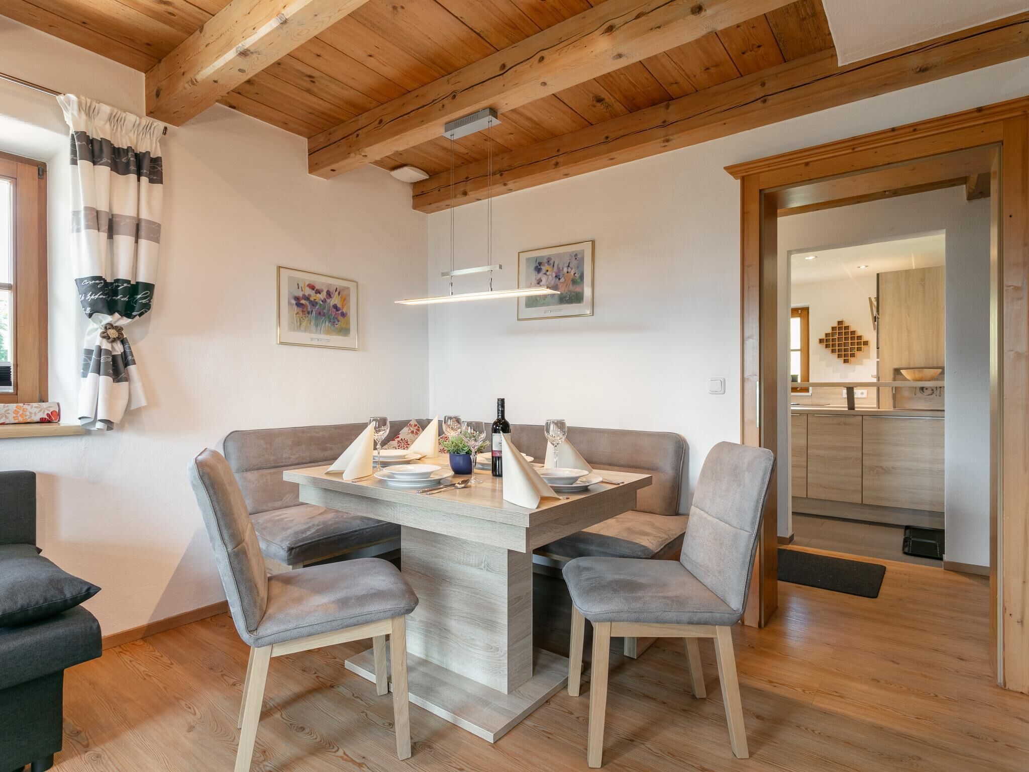 A dining area with a wooden table, grey upholstered chairs, and a wooden ceiling.