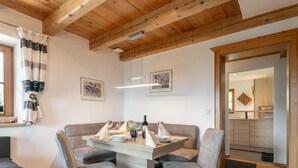 Et spiseområde med et træbord, grå polstrede stole og et træloft.