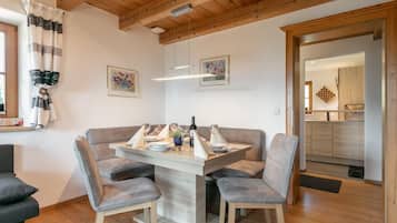 A dining area with a wooden table, grey upholstered chairs, and a wooden ceiling.