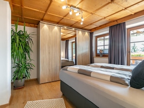 A bedroom with a bed, a potted plant, a wooden ceiling, and a window with curtains. - Exclusive holiday apartment with mountain view (Kirchberg in Tirol)