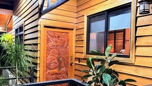 Une façade en bois agrémentée d’une porte décorative, d’une fenêtre et d’une balustrade.