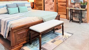 Une chambre à coucher avec un lit en bois, un banc, une table de chevet, un miroir et une plante en pot.