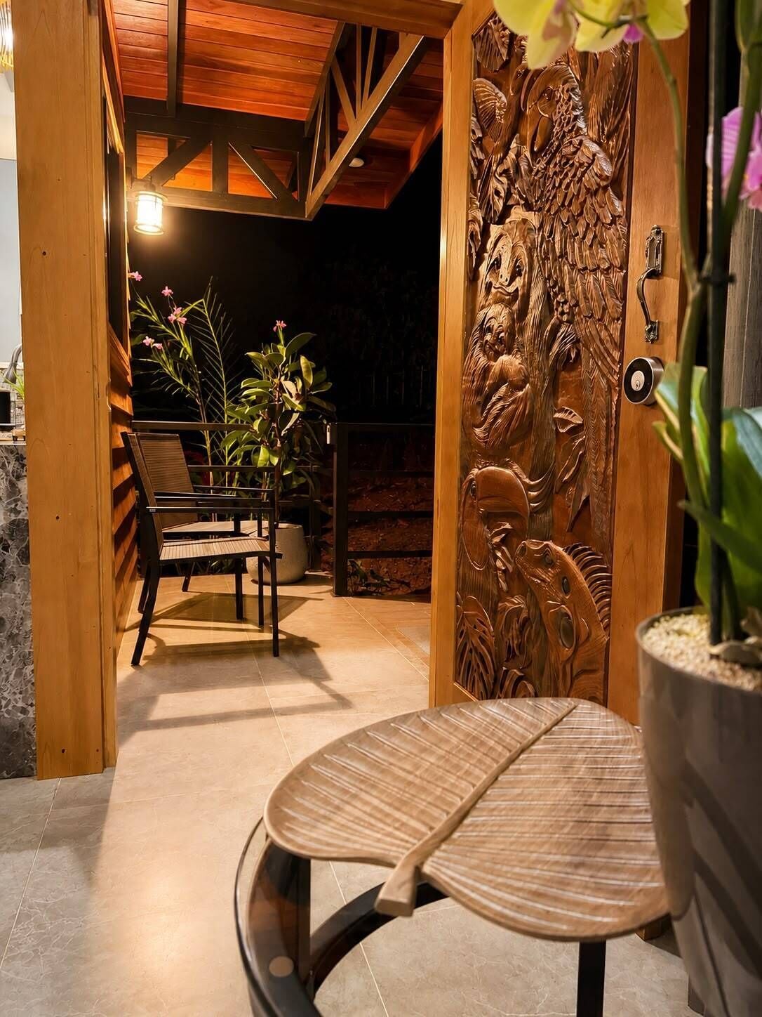 Une porte en bois ornée de sculptures complexes, un banc et une plante en pot.