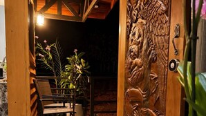 Une porte en bois ornée de sculptures complexes, un banc et une plante en pot.