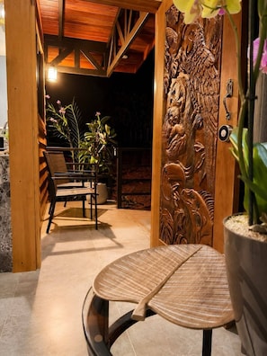 A wooden door with intricate carvings, a bench, and a potted plant. - Cabaña privada con jacuzzi en La Fortuna, Cerca del Volcan Arenal y Catarata. (Alajuela)