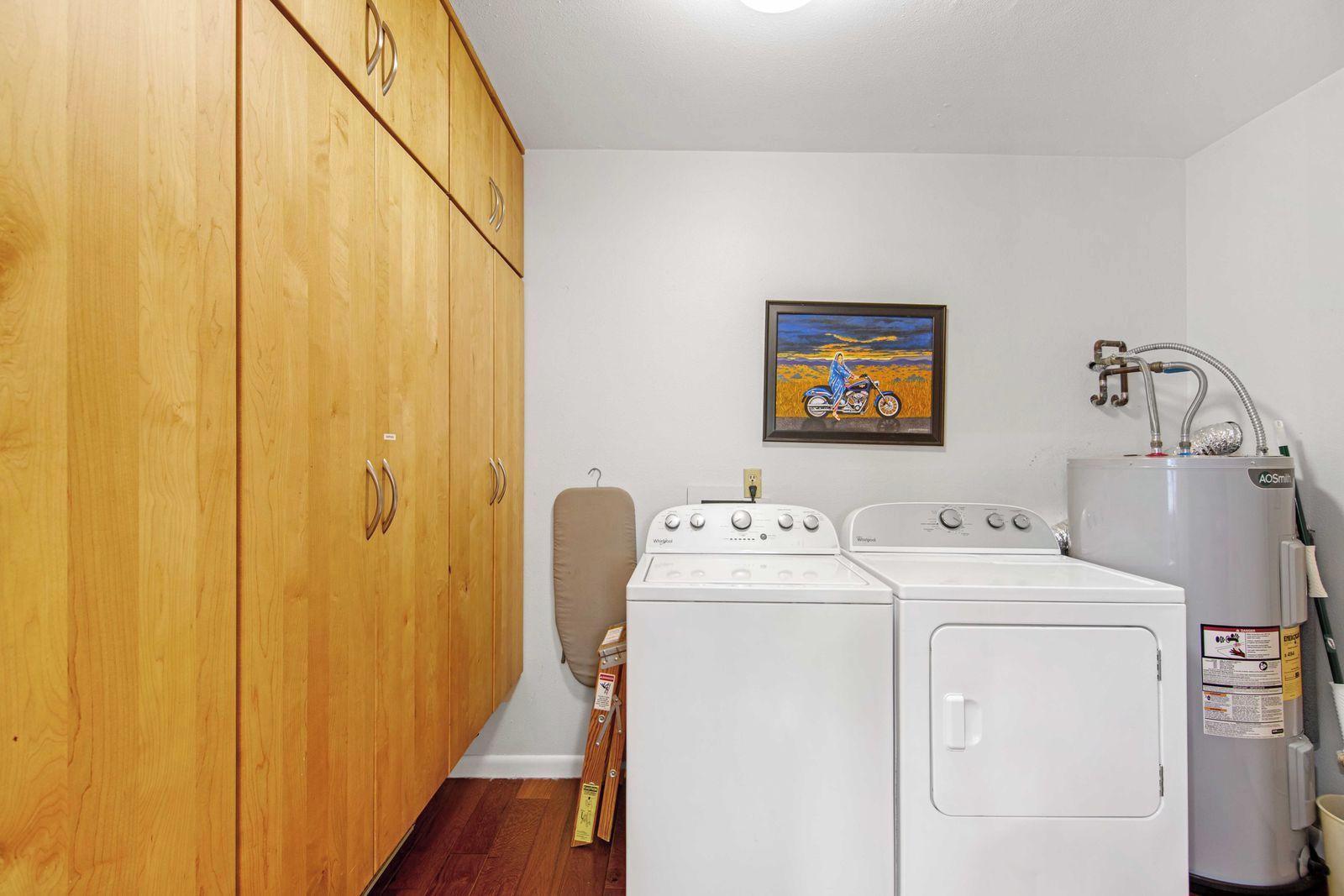 Une buanderie équipée de meubles en bois, d’un lave-linge, d’un sèche-linge et d’un chauffe-eau.
