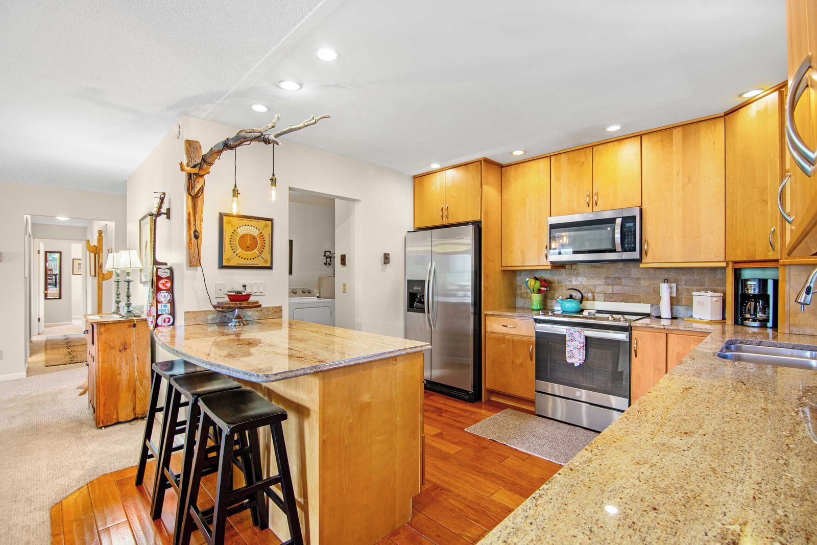 A modern kitchen with wooden cabinets, stainless steel appliances, and a central island with stools.