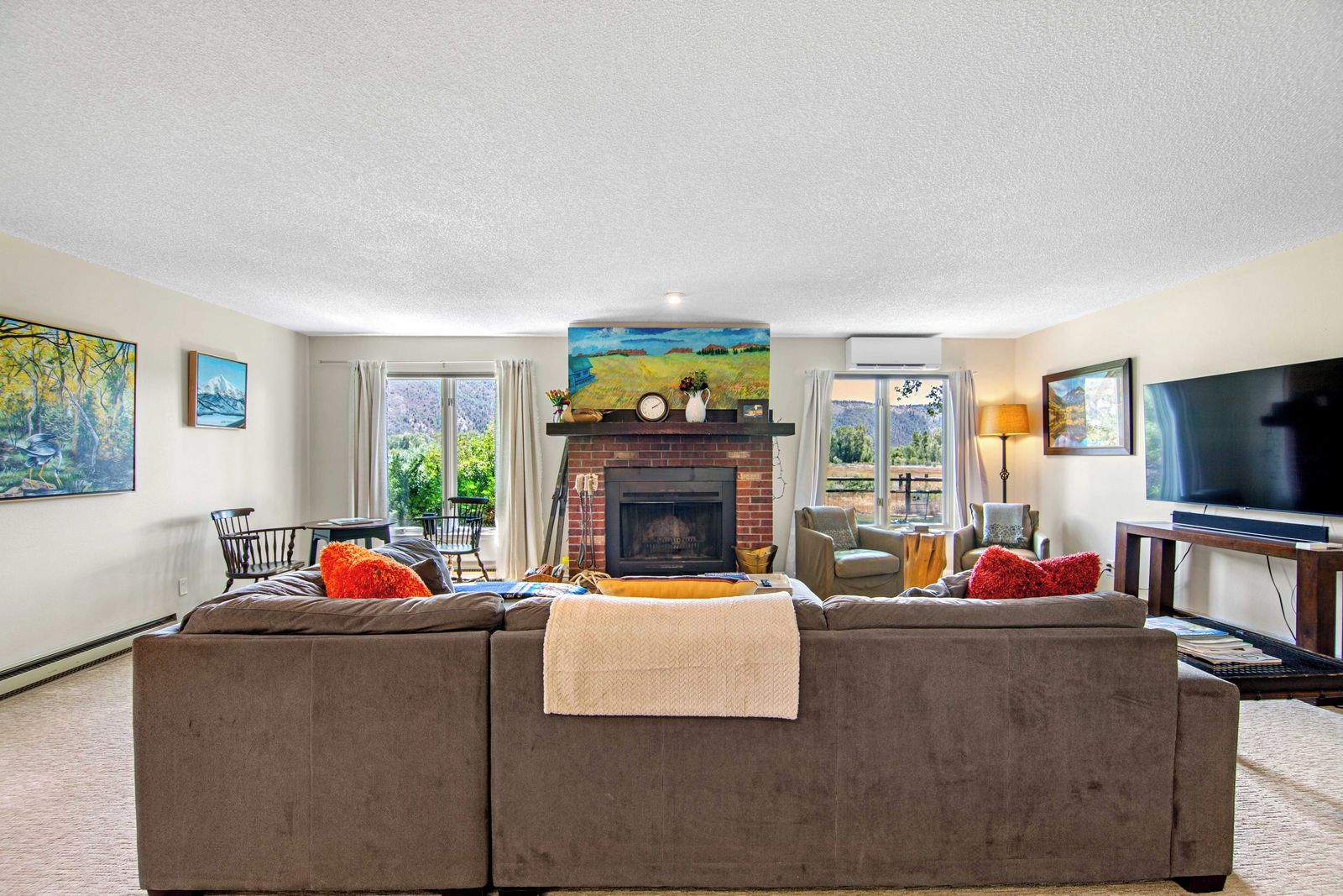 A living room with a fireplace, a sofa, a television, and artwork on the walls.