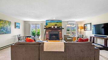 A living room with a fireplace, a sofa, a television, and artwork on the walls.