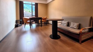 Een moderne kamer met een eettafel, stoelen, een bank en uitzicht op een gebouw door grote ramen.