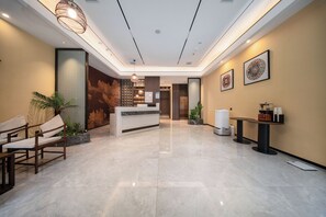 Um hall de hotel com balcão de recepção, área de estar e arte decorativa na parede.