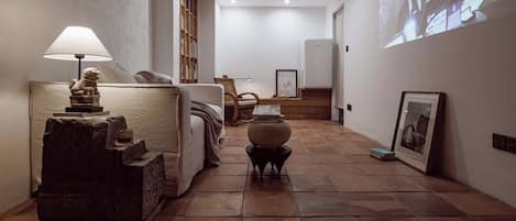 A hallway with a sofa, a lamp, a small table, and a projector screen displaying images.