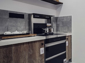 Een moderne keuken met een inbouwoven, een kookplaat en een houten aanrecht.