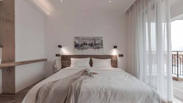 Un dormitorio moderno con una cama grande, un cuadro de un paisaje urbano y un balcón con cortinas.