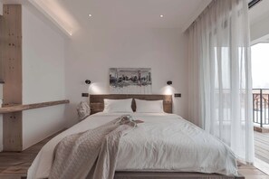Un dormitorio moderno con una cama grande, un cuadro de un paisaje urbano y un balcón con cortinas.