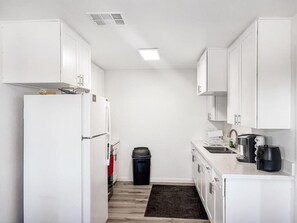 A compact kitchen with white cabinets, a refrigerator, a sink, and a coffee maker. - Charming 3-bedroom house with AC in serene Joshua Tree (Joshua Tree)