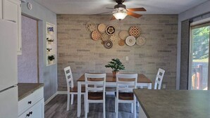 Un comedor con pared de ladrillo, ventilador de techo y una mesa con sillas.