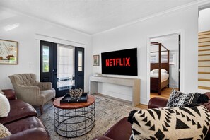 A modern living room with a television, a sofa, a coffee table, and a bed with a canopy. - Spacious home ft. backyard with exclusive hot tub! (Louisville)