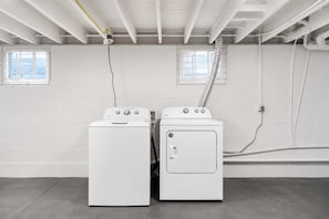A laundry room with two white washing machines, a ventilation system, and a window. - Spacious home ft. backyard with exclusive hot tub! (Louisville)