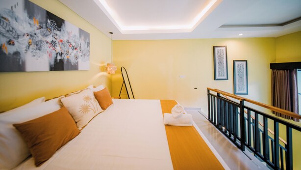 Una habitación de hotel con cama, obras de arte, una escalera y una barandilla.