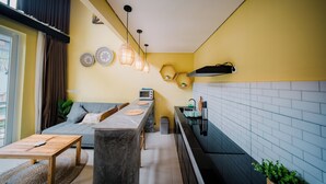Un espacio habitable compacto con kitchenette, un sofá, una mesa de comedor y una pequeña isla de cocina.