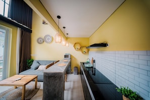 A compact living space with a kitchenette, a sofa, a dining table, and a small kitchen island. - The Loloan Loft (Badung)