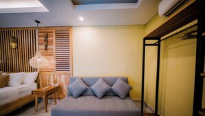 Una habitación con sofá, cama, una mesita y aire acondicionado instalado en la pared.