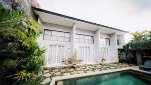 Una casa moderna con piscina, escalones de piedra y mobiliario exterior.