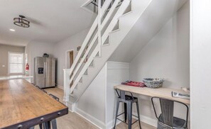 A modern kitchen with a wooden table, a built-in oven, and a stainless steel refrigerator.