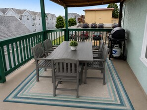 Eine überdachte Terrasse mit Tisch, Stühlen, einem Grill und einer Gasflasche.
