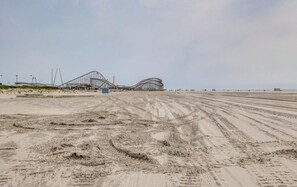 A beach with roller coaster tracks and a sandy area with tire tracks.