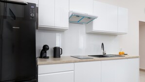Uma cozinha moderna com uma geladeira preta Hisense, forno embutido, cafeteira e pia com torneira.