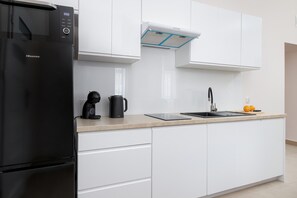 Una cocina moderna con un refrigerador Hisense negro, un horno empotrado, una cafetera y un lavamanos con grifo.