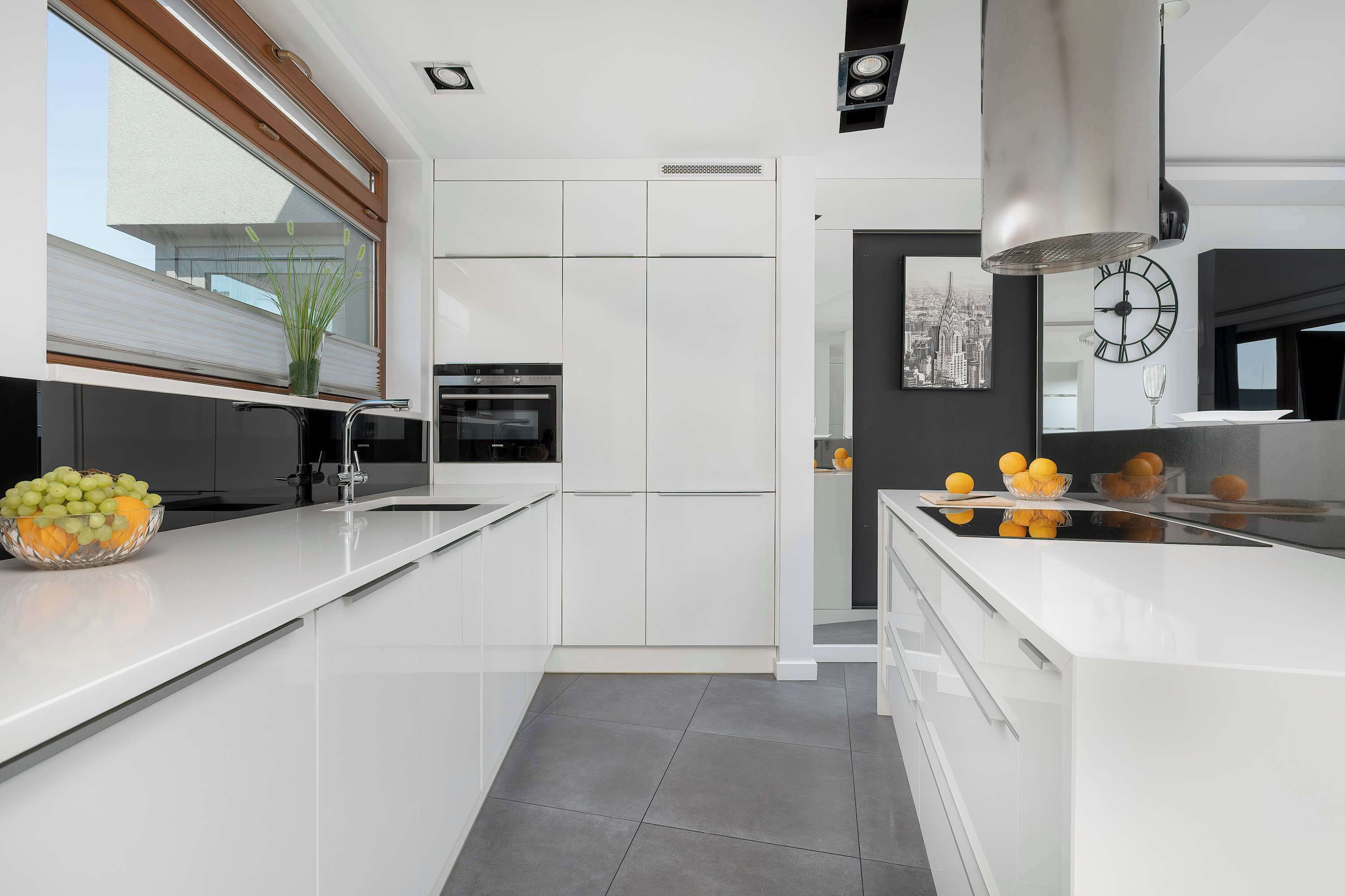 Een moderne keuken met witte kastjes, een inbouwoven en een groot raam met uitzicht.