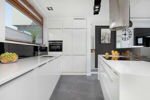 Una cocina moderna con armarios blancos, horno empotrado y un amplio ventanal con vistas.