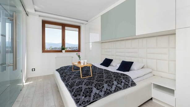 A modern bedroom with a bed, bedside tables, a window with a view, and a radiator. - Stylish Apartment with a Balcony | Close to City Center (Bielsko-Biała)