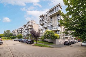 A modern apartment building with multiple balconies and a parking area. - Cozy Studio Near the Wisla River | Balcony | Zabłocie (Kraków)